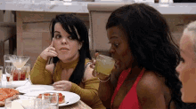 a group of women are sitting at a table drinking and eating pizza .
