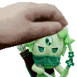 a hand is holding a green figurine with a bow and arrow on it .
