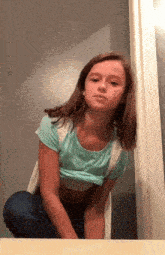 a young girl in a crop top and jeans is sitting on a table