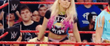 a woman is standing in the middle of a wrestling ring in front of a crowd .
