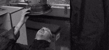 a black and white photo of a man working on a machine in a factory .