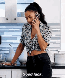 a woman is talking on a cell phone while standing in a kitchen .