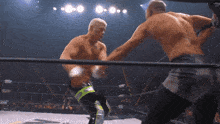 two men are fighting in a wrestling ring and one of them is wearing shorts with the word aew on them
