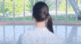 a woman in a white shirt stands in front of a window