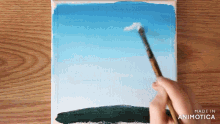 a person is painting a blue sky with a brush and the words made in animatica on the bottom right