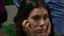 a close up of a woman 's face with her hands on her chin