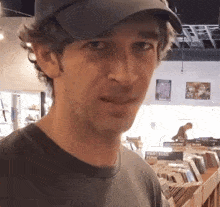 a man wearing a hat and a grey shirt is standing in a record store .