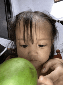 a baby is eating a green watermelon and looking at the camera