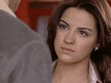 a woman in a satin shirt and pearl earrings is looking at a man .
