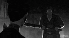 a black and white drawing of a man holding a bat with a netflix logo behind him