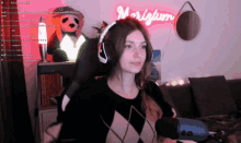 a woman wearing headphones is sitting in front of a neon sign that says " magnilum "