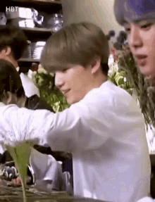 a man in a white shirt is standing in front of a table with flowers in it .
