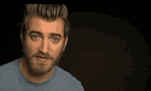 a man with a beard wearing a blue shirt is making a funny face .