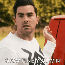 a man in a white shirt is holding a key in front of a red van and says okay fine you win