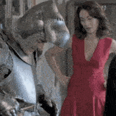 a woman in a red dress is standing next to a knight in armor