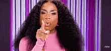 a woman in a pink shirt is pointing at the camera .