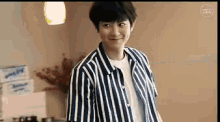 a young man wearing a striped shirt and a white shirt is standing in a room .