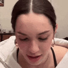 a close up of a woman 's face with her eyes closed and a white shirt .