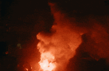 a large fire with smoke coming out of it in the dark