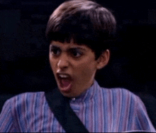 a young man in a striped shirt is making a surprised face