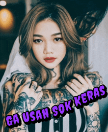 a woman with a lot of tattoos on her arms and the words ga usaha sok keras