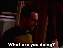a man is standing in a dark room and asking what are you doing ?