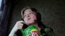 a man wearing headphones is holding a bag of lay 's chips