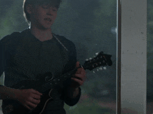a man playing a guitar with the letter g on the neck