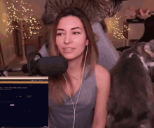 a woman is sitting in front of a microphone with a cat on her head behind her