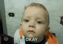 a baby is making a funny face and says okay .