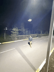 a man in a black jacket stands on the side of the road at night