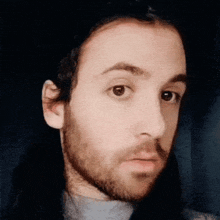 a close up of a man 's face with a beard and long hair