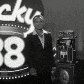 a man in a suit stands in front of a lucky 38 sign
