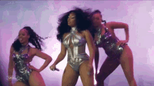 a woman in a silver swimsuit is dancing with two other women