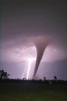 a tornado is being struck by lightning in a field at night
