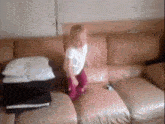 a little girl is jumping on a couch in a living room .