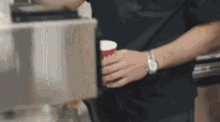 a man is holding a cup of coffee in his hand .