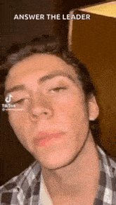 a young man in a plaid shirt is making a funny face while looking at the camera .