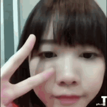 a close up of a girl making a peace sign with her fingers on her face .