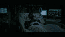 a man laying in a hospital bed with a monitor showing his heart rate
