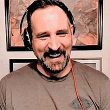 a man wearing headphones is smiling in front of a framed picture that says ' evian ' on it