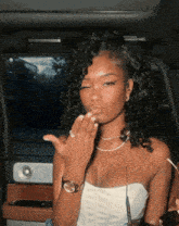 a woman with curly hair blowing a kiss in a car