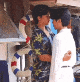 two men are kissing in front of a life preserver .