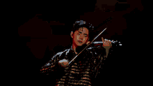 a young man is playing a violin on a stage in front of an orange background