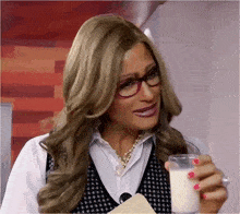 a woman in a wig and glasses is drinking a glass of milk