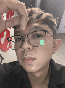 a young man wearing glasses holds his hand to his face