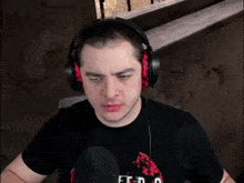 a man wearing headphones is sitting in front of a microphone and making a funny face .
