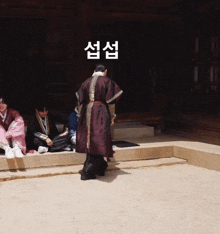 a man in a kimono stands in front of a group of people sitting on steps