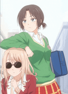 a girl wearing sunglasses is standing next to another girl wearing a green sweater