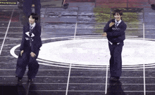 two men in suits and ties are dancing on a stage in front of a sign that says ' nss '